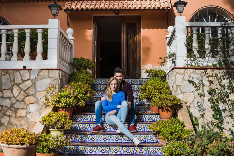 Casal sentado nas escadas de uma moradia