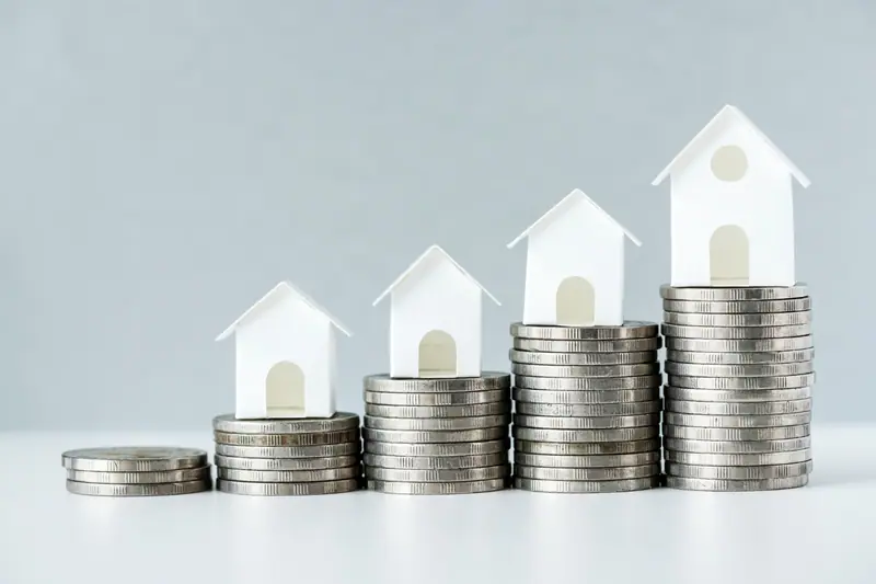 Stacks of coins and small houses, illustrating rising rents in Portugal